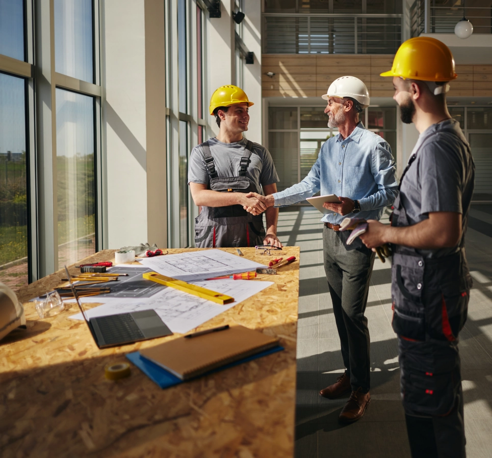 Architect and workers shaking hands in construction.