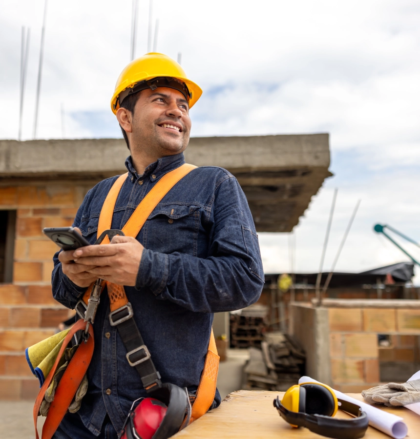 Smiling construction worker holding a smartphone.