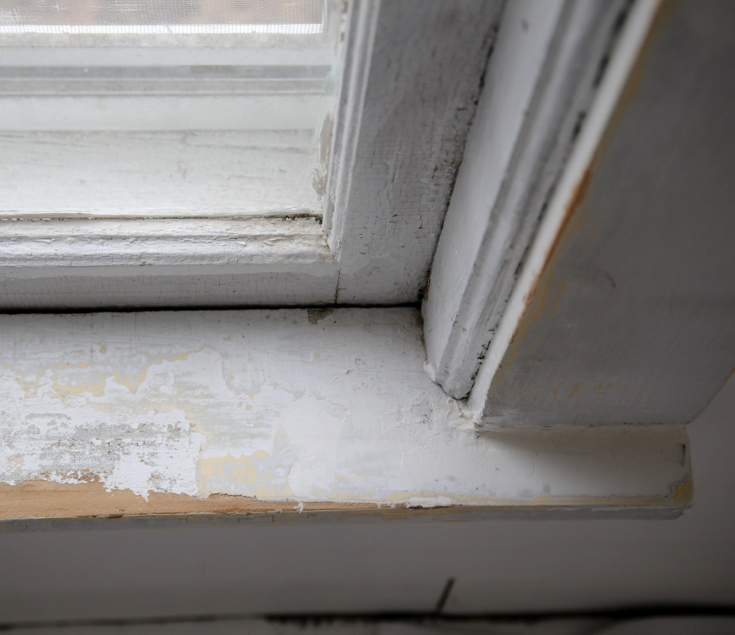 Peeling paint on old wooden window frame.